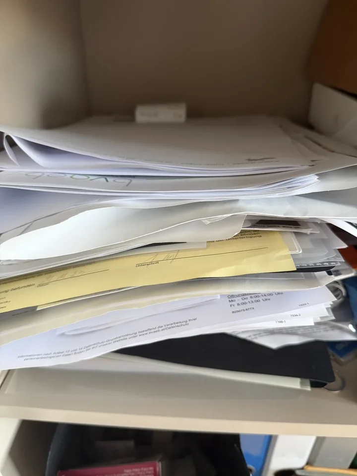 Unsortierter Papierstapel mit offenen Briefen, Fristen und Nachweisen.